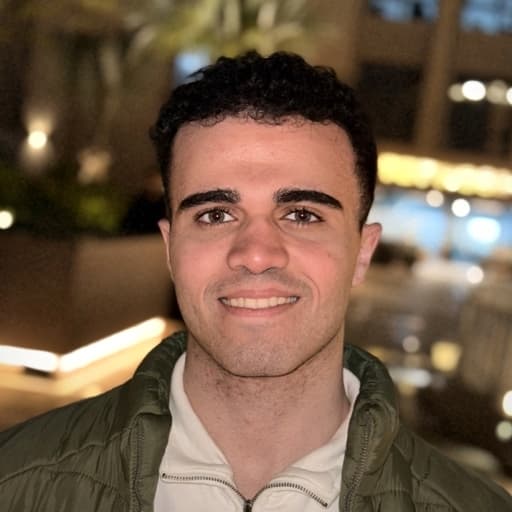 Adham Ahmed Altony at night in Cairo, warm city lights glowing behind him