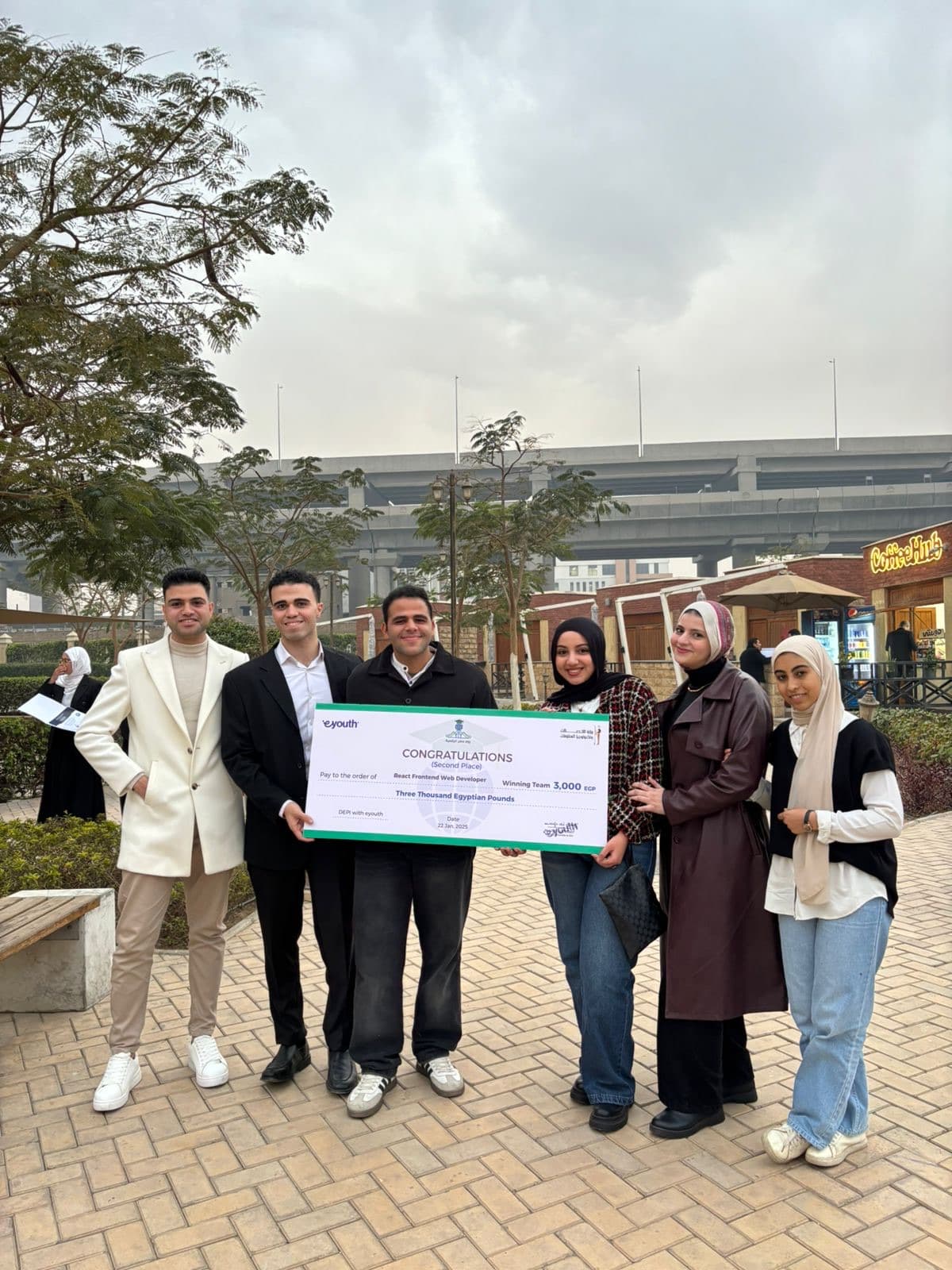The six-person SehaTalk team holding the DEPI React track 2nd-place check at the graduation ceremony in Cairo